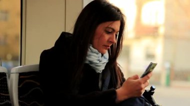 Tramvay ulaşımı sırasında cep telefonuna bakan bir kadın. Akıllı telefon teknolojisine bakan banliyö çalışanı