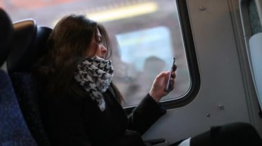 Trende cep telefonu kullanan bir kadın. Akıllı telefonunu kontrol eden e-postalarını kontrol eden ve hareket halindeki trende aletle internette sörf yapan bir kız.