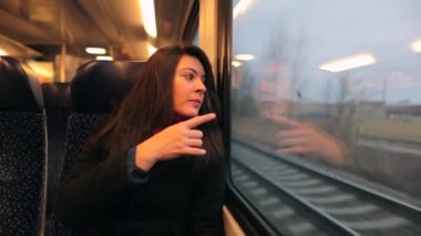 Trenle seyahat eden genç bir kadın manzaranın önünden geçtiğini gösteriyor..