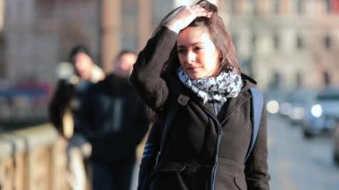 Kaldırımda yürüyen bir kadın kameranın önünden geçiyor. Kız şehrin sokaklarında soğuk kış sezonunda 4K 60fps yavaş çekim yürür