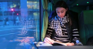 Otobüsle seyahat eden ve geceleri kitap okuyan yolcu