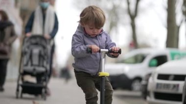 Sokakta scooter süren bir çocuk. Küçük çocuk scooter kullanıyor.