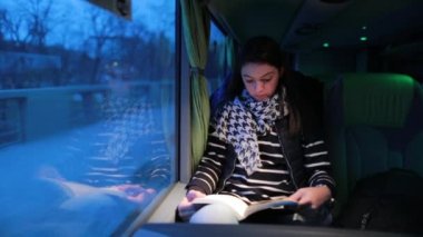 Otobüsle seyahat eden bir kadın. Hareket halindeki bir araçta seyahat ederken kitap okuyan bir kız
