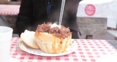 Budapeşte 'deki yıllık Noel pazarında ekmek kasesinde Gulaş yiyen turist kız. Turistler geleneksel Macar mutfağının tadını çıkarıyorlar.
