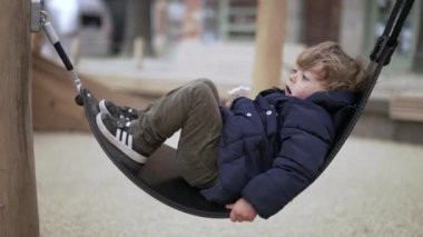 Çocuk dışarıda hamakta yatıyor.