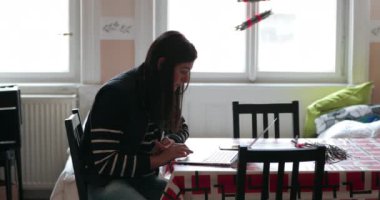 Evde çalışan bir kadın mutfak masasından interneti karıştırıyor. Kız evden internette sörf yapıyor.