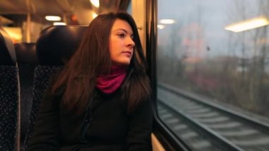 Trenle seyahat eden genç bir kadın yanından geçen manzaraya bakıyor. Hareket halindeki trende oturan kız 120 fps yavaş çekimde dışarı bakıyor.