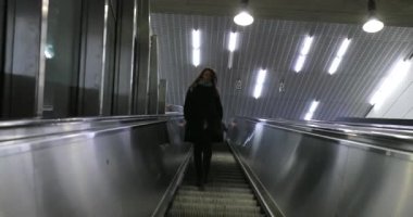 Modern elektrikli yürüyen merdivenlerden inen bir kadın. 4K ile merdivenlerden inen kız.