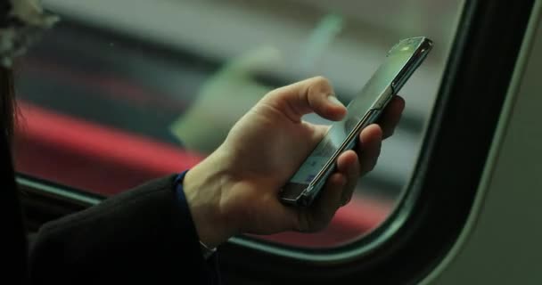 移動中の電車の中で携帯電話をチェックする人の手 通勤や電車で移動中のコンテンツのスクロールや選択に触れる手 — ストック動画