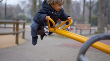 Küçük bebek tahterevallide oynuyor.