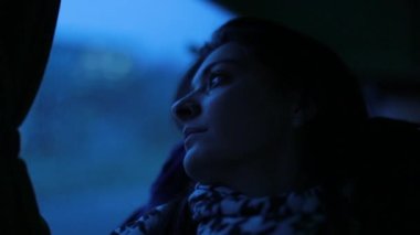 Akşamları pencereden bakan bir kız. Kadın gece yolculuk yaparken otobüs camından dışarı bakıyor.