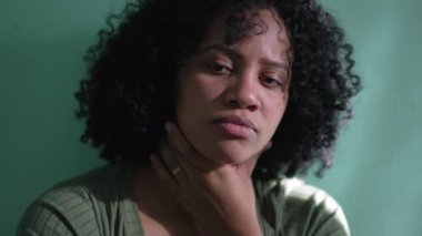 Afro-Amerikalı düşünceli kadın. Düşünceli siyah bir kız duvara yaslanıyor çene kemiğinde çözeltiyi düşünüyor.