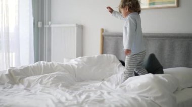 Sevimli bebek sabahları yatakta zıplıyor ve düşüyor