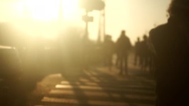 Bulanık şehir ortamı, caddeden karşıya geçen insanlar.