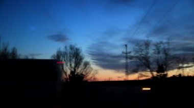 Gün batımında hayallere dalan manzaralı bir yoldan geçen bir peyzaj. Siluetli ağaçlar ve yoldaki elektrik kabloları