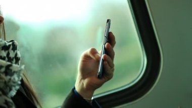 Modern ulaşım araçlarıyla seyahat eden ve akıllı telefon cihazını kontrol eden kadın.