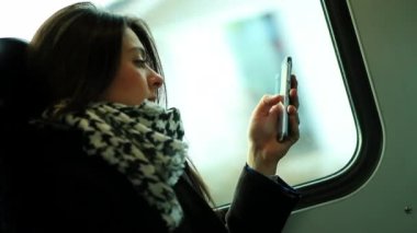 Tren ulaşımı sırasında cep telefonu teknolojisini kontrol eden bir kadın.