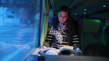 Gece otobüsle seyahat ederken kitap okuyan kadın