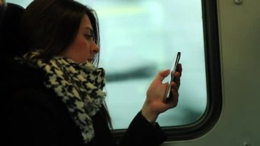 Kadın trende giderken cep telefonu teknolojisine bakıyor.