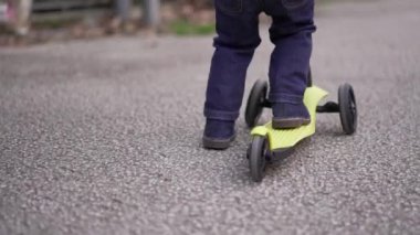 Çocuk parkta oyuncak scooter kullanıyor.