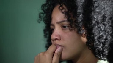 Afro-Amerikalı düşünceli kadın. Düşünceli siyah bir kız duvara yaslanıyor çene kemiğinde çözeltiyi düşünüyor.