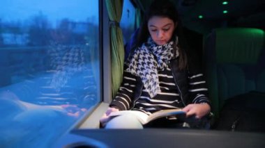 Otobüsle seyahat eden bir kadın. Hareket halindeki bir araçta seyahat ederken kitap okuyan bir kız
