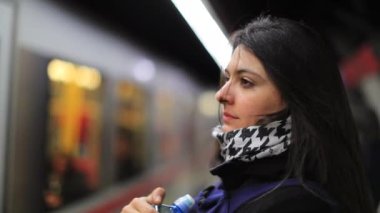 Metro perona yanaşıyor. Kadın modern ulaşım metro sistemine girmek üzere. Kız platformda duruyor ve trenin gelmesini bekliyor.