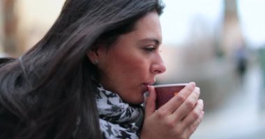 Kadın sıcak içeceği soğutmak için üflüyor. Soğuk mevsim boyunca düşüncelere dalmış sıcak içecek içen bir kız.