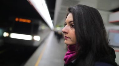 Treni seyreden bir kadın platforma yavaş çekim 120 fps hızla geliyor. Tren geldiğinde metro istasyonundaki bir kızın portresi.