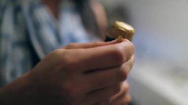 Şampanya mantarı iten ellerin yakın çekimi. Kadın şampanya şişesini açıyor.