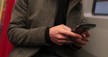 4K 'da metro metrosundayken cep telefonu cihazıyla daktilo eden adamın yakın çekimi.