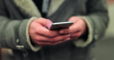 Cep telefonu cihazını elinde tutan, akıllı telefondan internete girip arkadaşlarına mesajlarını kontrol eden 4K metro platformunda arkadaşlarına mesaj atan biri.