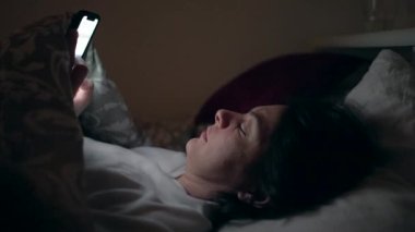 Anne ve bebek gece yatağa uzanmış ellerinde telefon ekranı tutuyorlardı.