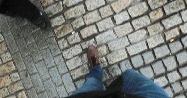 Şehir ortamında orta çağ kaldırım taşları üzerinde yürüyen botları olan bir adam. 4K 'da yürüyen kişinin bakış açısı