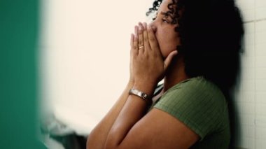 Korkak bir genç siyahi kadın yerde oturmuş utançla yüzünü örtüyor. Korkmuş Afrikalı Amerikalı Brezilyalı kız yalnızlıktan muzdarip