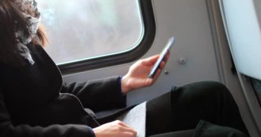 Hareket halindeki bir trende giderken cep telefonunu kontrol eden bir kadın.