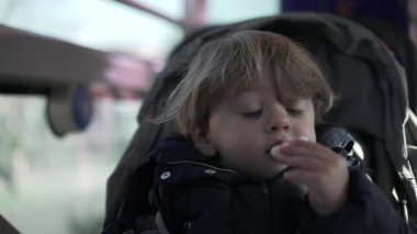 Küçük çocuk otobüs içinde abur cubur yiyor.