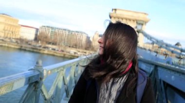 Mutlu turist kız bir köprünün tepesindeki Avrupa kasabasını ziyaret ederek şehirde yürüyor. 120fps yavaş çekimde yürürken saçları düzenleyen kadın.