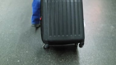 Tekerlekli bavul taşıyan kişi.
