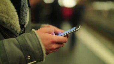 Metro istasyonundaki banliyö görevlisi e-postaları kontrol ediyor ve cep telefonu aygıtında interneti tarıyor.