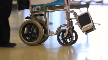 Sürüklenen tekerlekli sandalye. Katlanmış tekerlekli sandalye taşıyan kişiye yakın çekim