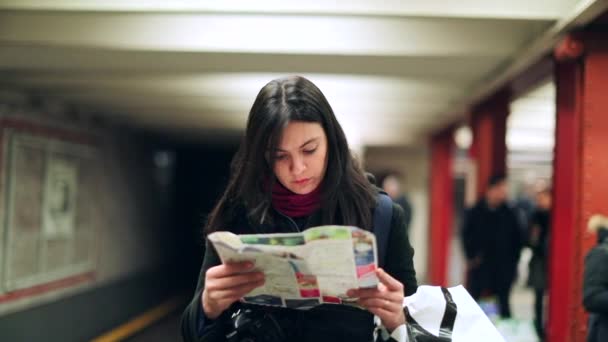 妇女检查纸质地图的方向 真实坦率的现实生活中的人在地下铁站台上看地图就知道该去哪里 — 图库视频影像