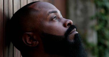 Gözleri kapalı düşünceli siyah bir adam. Dalgın Afrikalı adam gözlerini açıyor