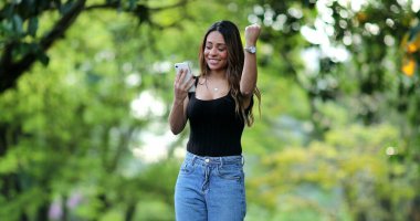 İspanyol kadın dışarıda cep telefonuyla iyi haberleri kutluyor.