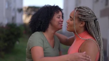 Birbirlerine sarılan iki genç zenci kadın. Yetişkin kız arkadaşlar kucaklaşır. İnsanlar empatik kucaklaşma.