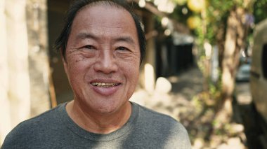 Closeup face of a Japanese man standing in street looking at camera. Middle aged Asian person
