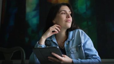 Tablet aletini tutarken bir fikir düşünen düşünceli bir kadın. Düşünceli kişi çevrimiçi içeriği arıyor