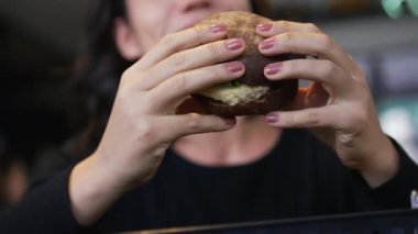 Hamburger yiyen biri. Kapanış kızı elinde lezzetli fast food burgeri tutuyor.