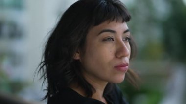 Düşünceli, kendine güvenen Brezilyalı bir kadın ciddi bir ifadeyle karşı karşıya.