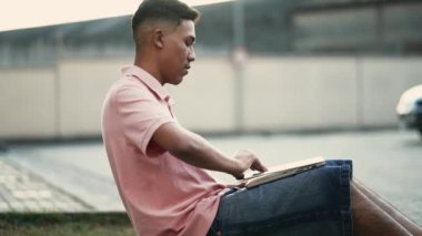 Genç Brezilyalı adam bilgisayarını uzaktan çalışmada ya da çalışmada açıyor.